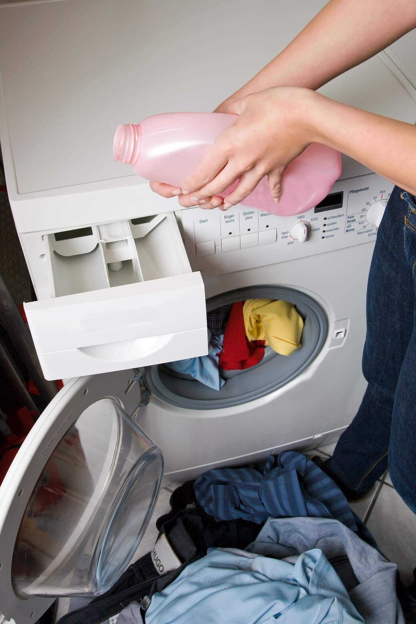 A person putting laundry detergent into a washing machine