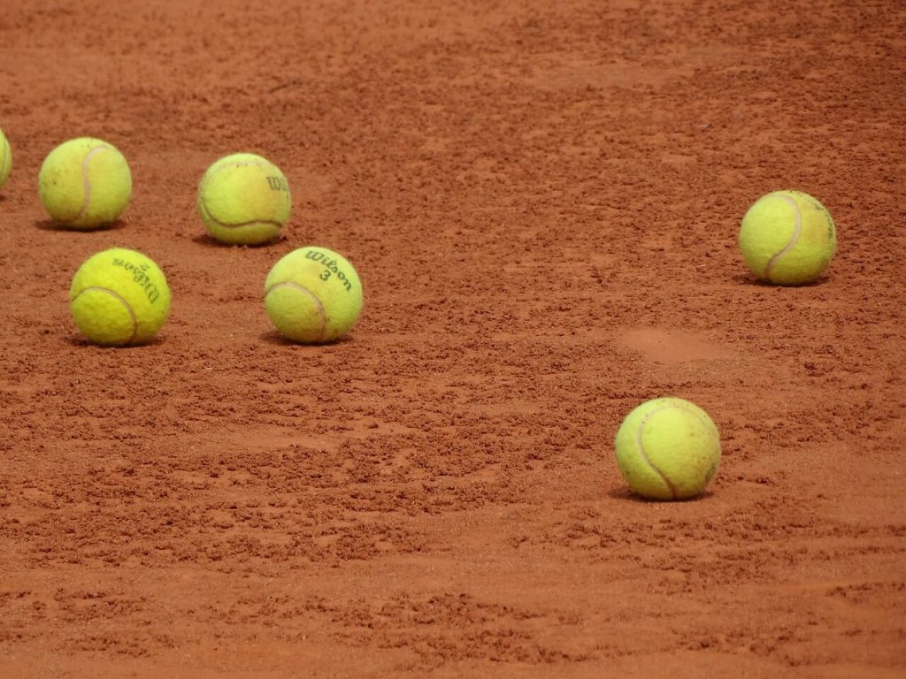 A group of tennis balls on a clay court