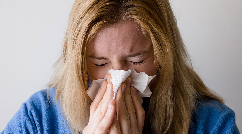 woman blowing her nose as an allergic reaction