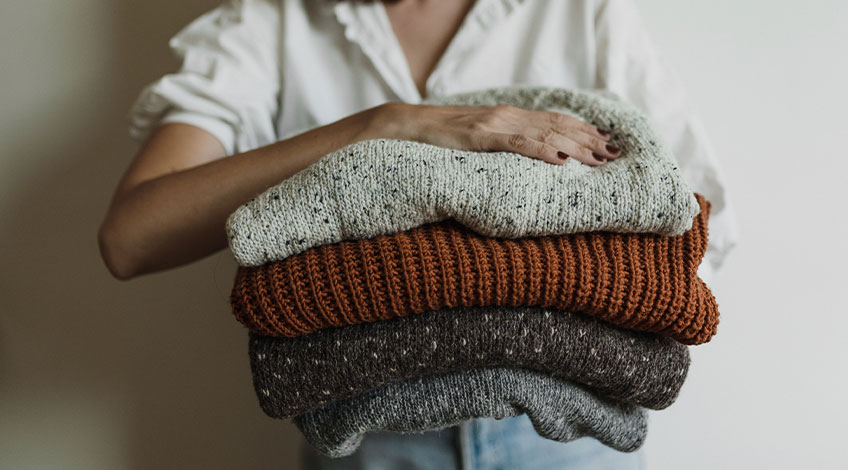 woman holding knitted wool sweaters