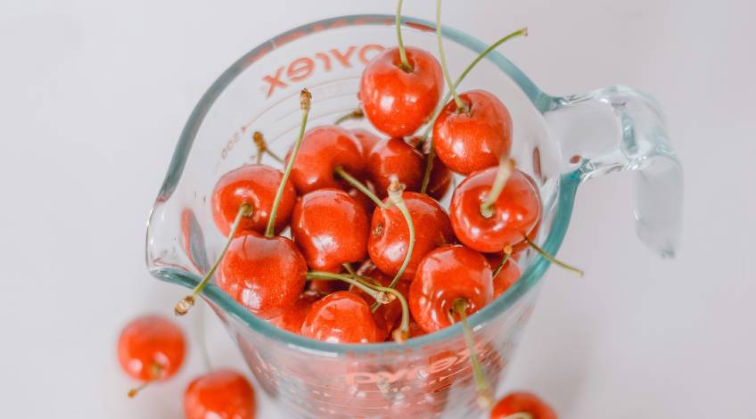 Pyrex glass measuring cup filled with cherries
