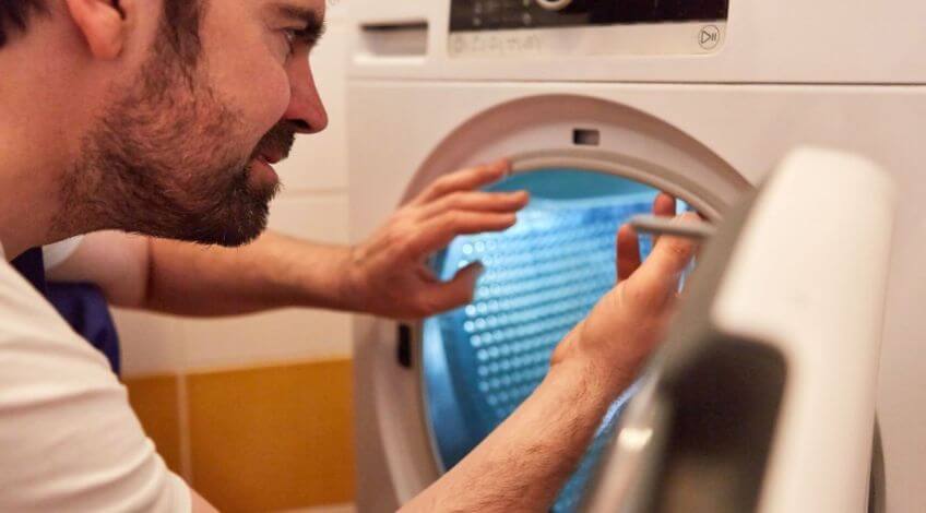 man looking inside a tumble dryer