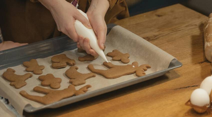 person decorating cookies on a baking tray with wax paper