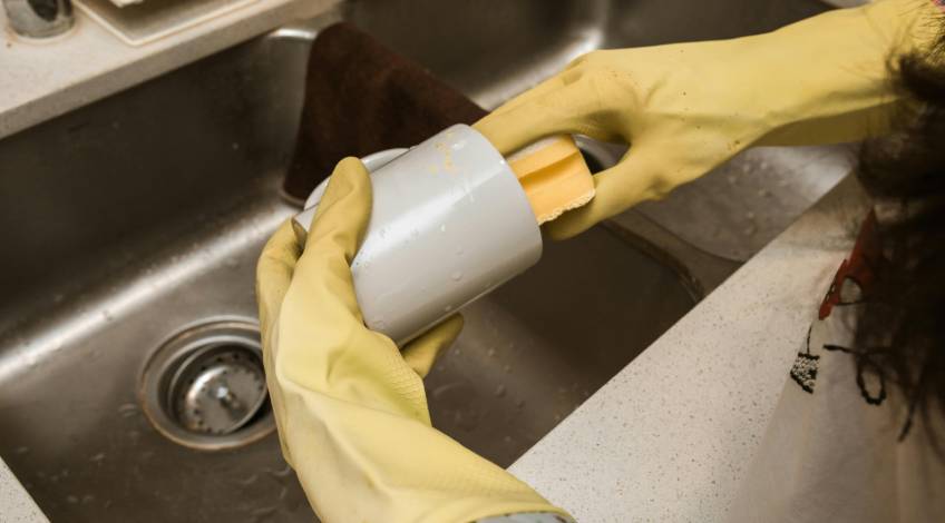person washing dishes wearing rubber gloves
