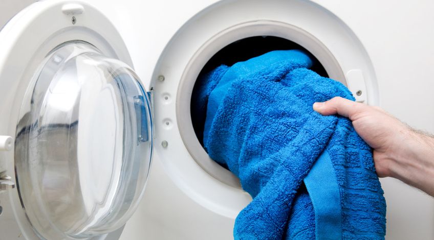 person putting a towel in a tumble dryer