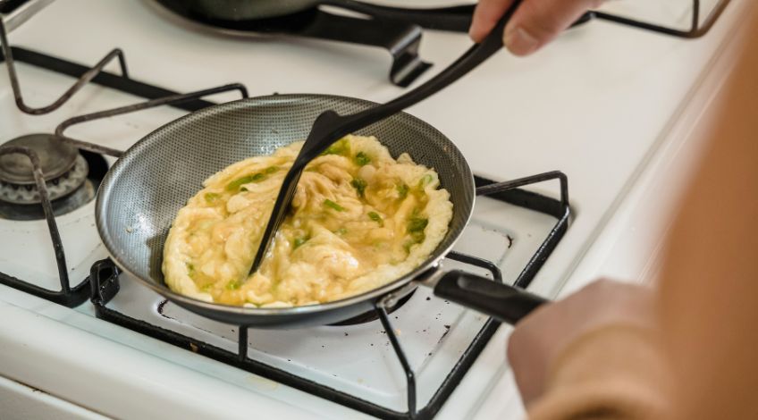 person cooking scrambled eggs
