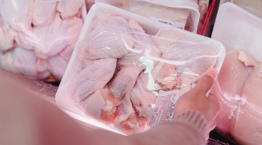 person holding raw poultry on a tray