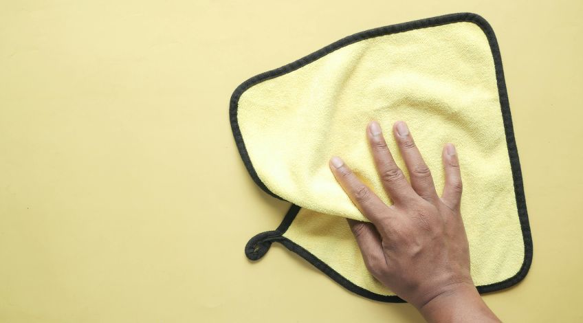 person holding a yellow microfibre cloth