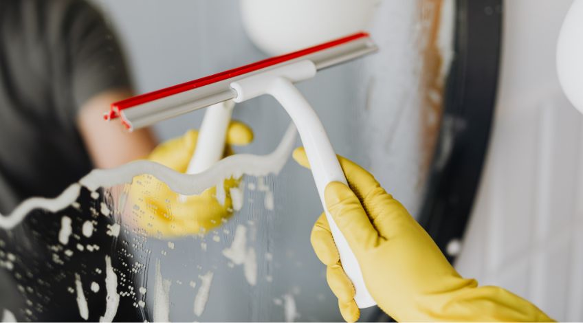 person drying mirror with squeegee